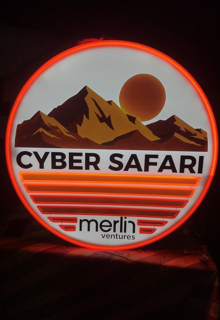 Round backlit sign with a mountain and sun graphic and a glowing orange LED edge