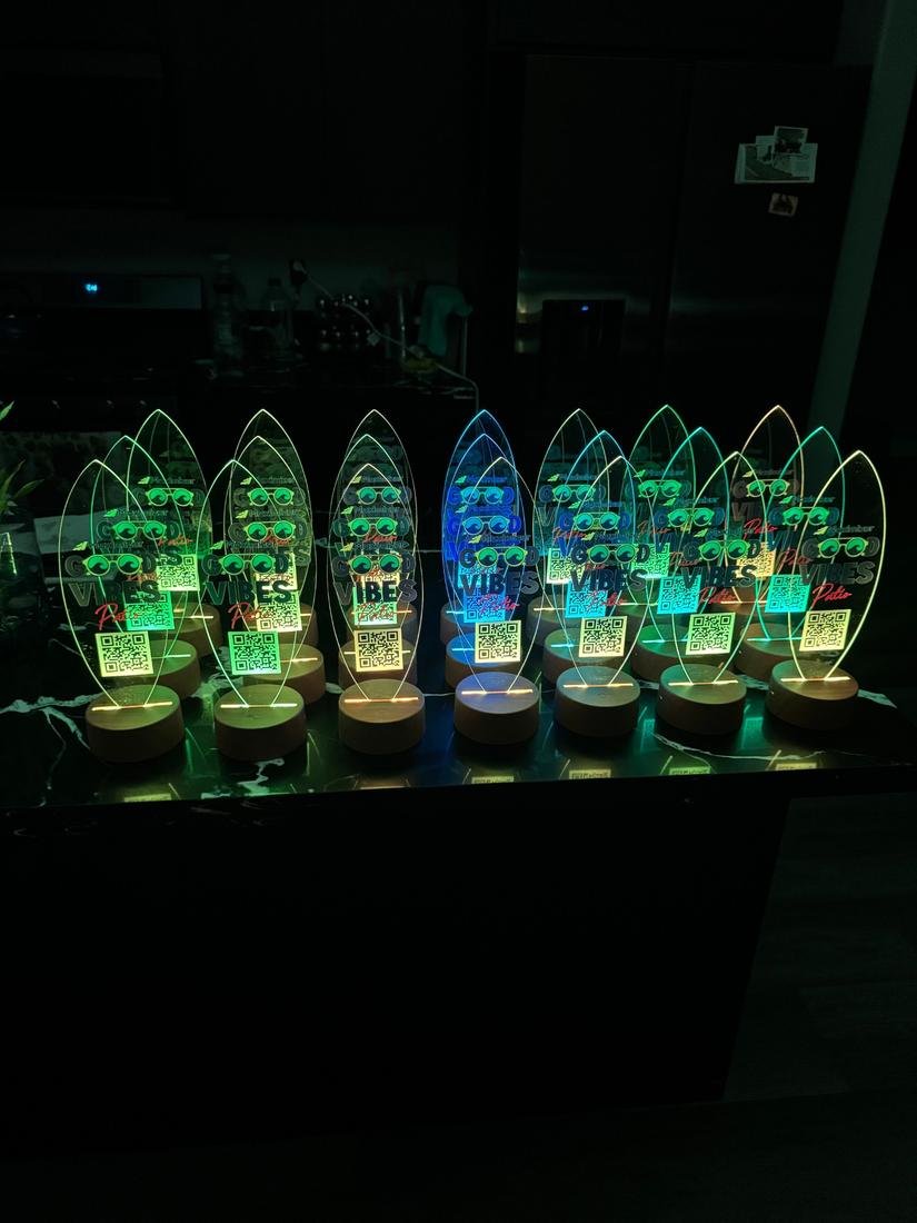 Rows of surfboard shaped acrylic pieces on wooden bases glowing in changing colors, each with a printed logo and QR code