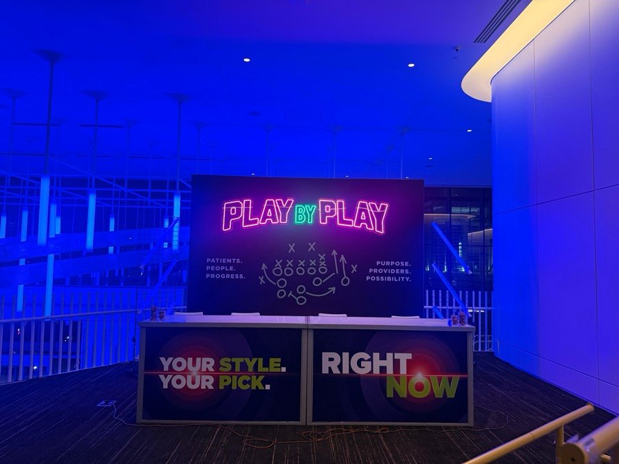 Neon style Play By Play sign on a backdrop wall at a corporate event